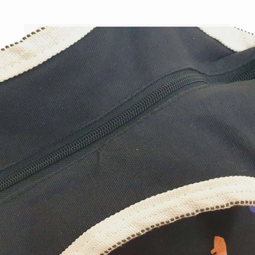 Close-up of a black bag with white trim and a zipper