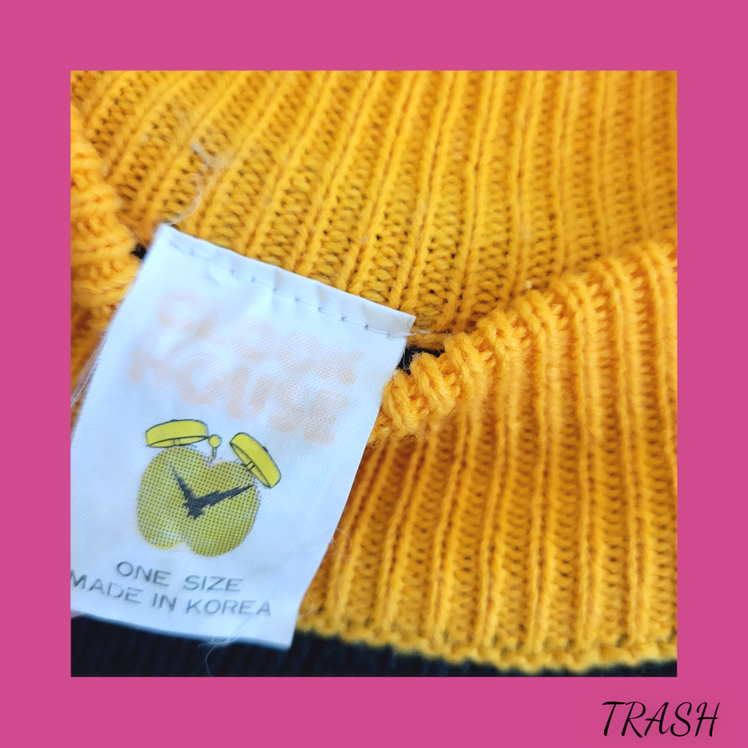 Yellow knitted garment with a label on a pink background