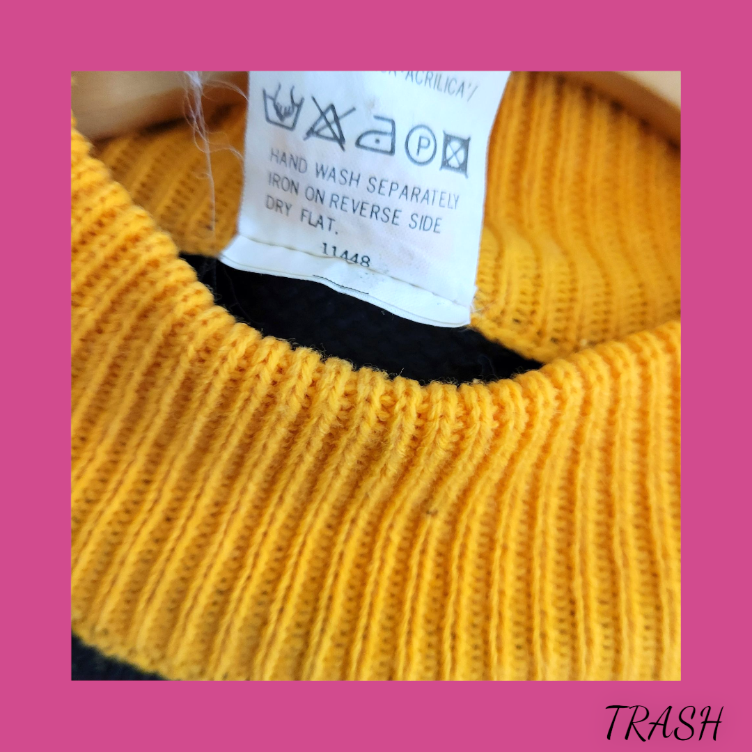 Close-up of a yellow knitted garment with a care label on a pink background