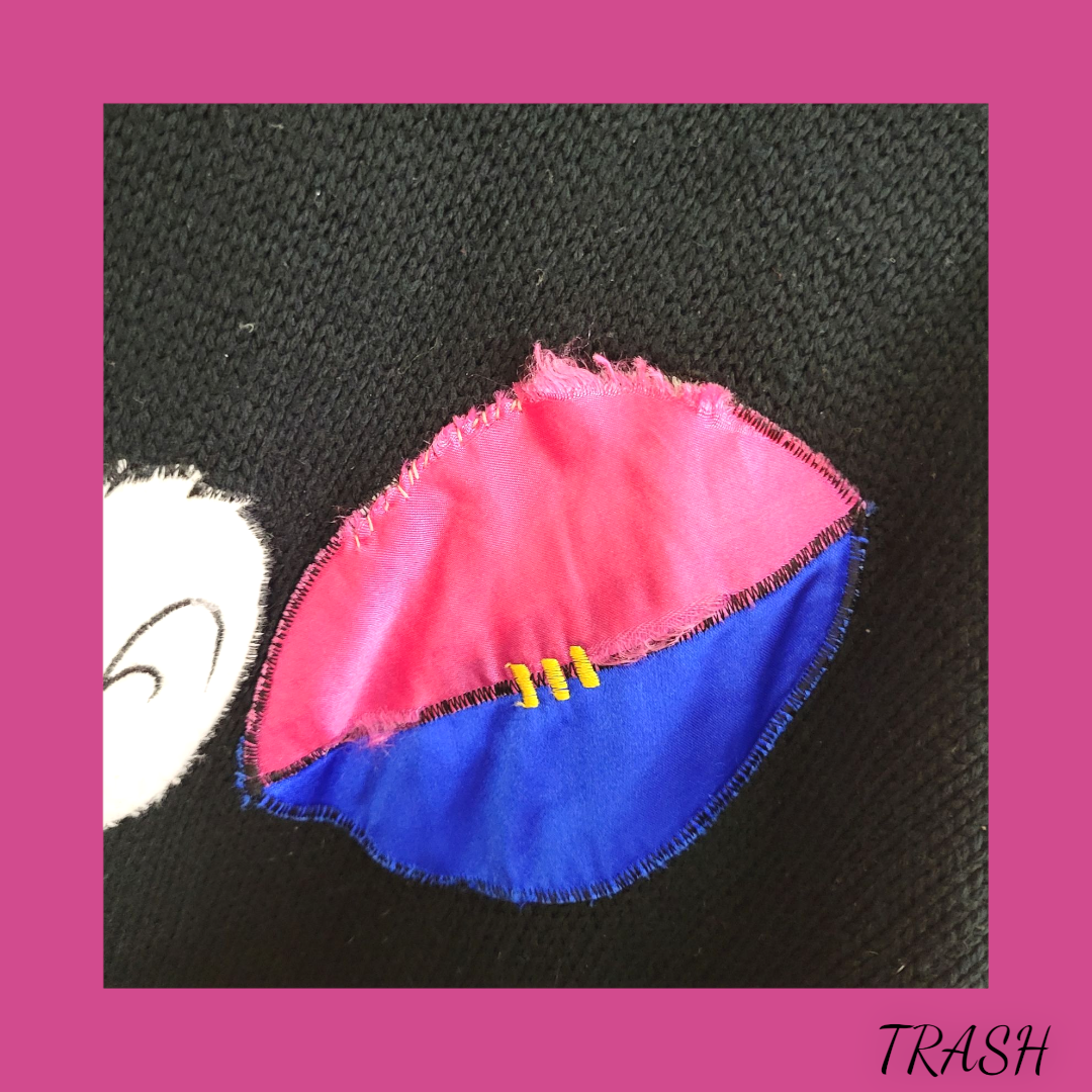 Pink and blue fabric patch on black fabric with 'TRASH' label